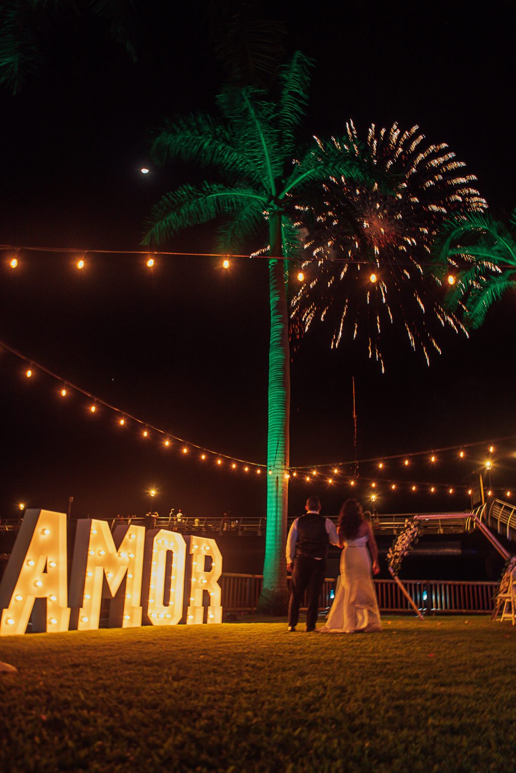 Novios frente a las letras AMOR con fuegos artificiales en Oscar's Puerto Vallarta